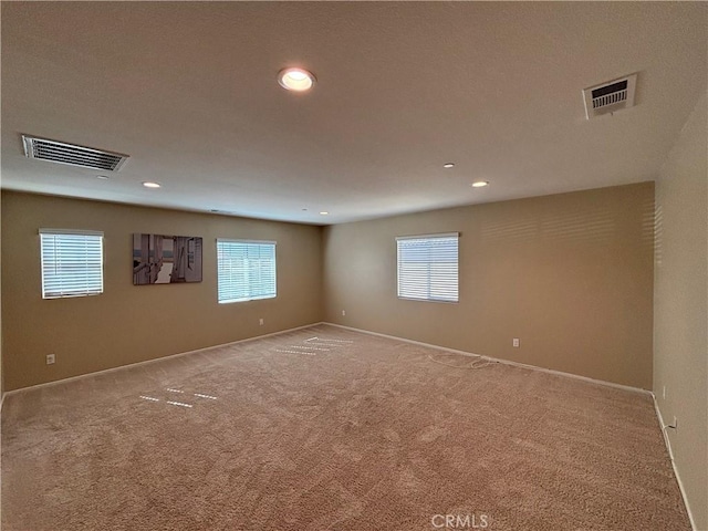 empty room with carpet, visible vents, and recessed lighting