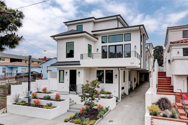 view of front of house with stairway, fence, a vegetable garden, and stucco siding