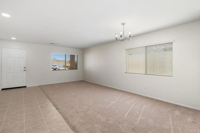 empty room featuring a notable chandelier, recessed lighting, light carpet, light tile patterned flooring, and baseboards