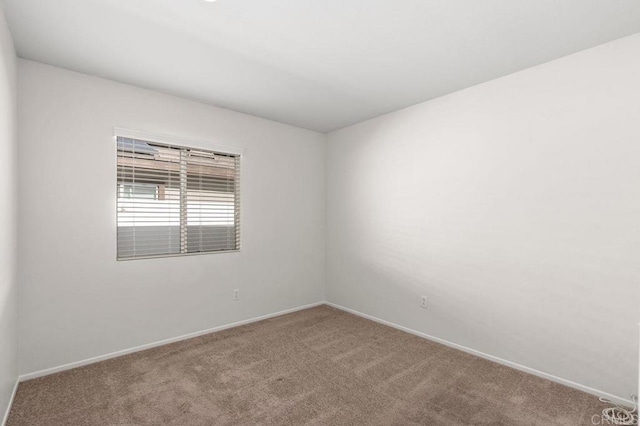 carpeted empty room featuring baseboards