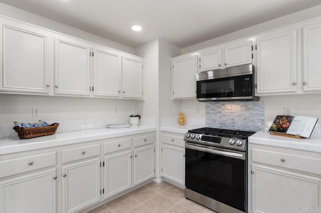 kitchen featuring stainless steel appliances, tile counters, and white cabinetry