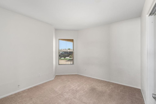 empty room featuring light colored carpet and baseboards