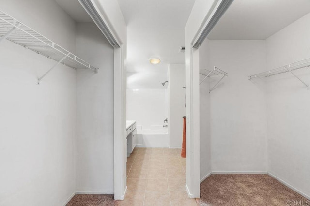 spacious closet featuring light tile patterned floors and light carpet