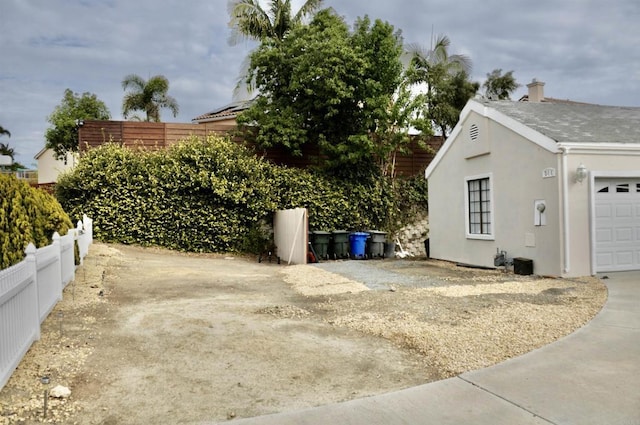 view of property exterior featuring a garage, driveway, fence, and stucco siding