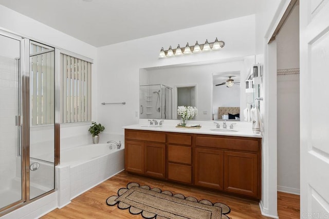 bathroom with wood finished floors, a stall shower, and a sink