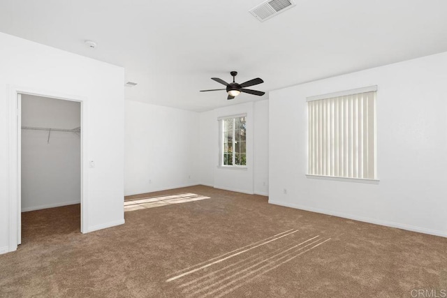 unfurnished bedroom featuring carpet floors, a spacious closet, visible vents, and baseboards