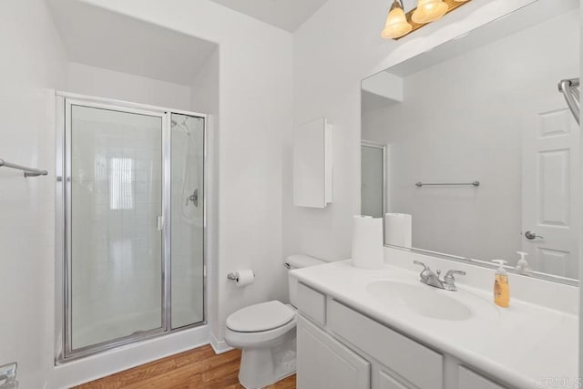 bathroom featuring a stall shower, vanity, toilet, and wood finished floors