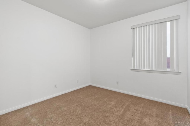 unfurnished room featuring carpet and baseboards