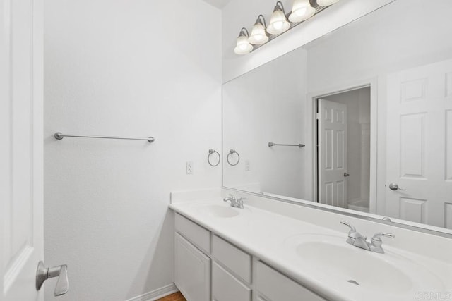 bathroom with double vanity, a sink, and baseboards