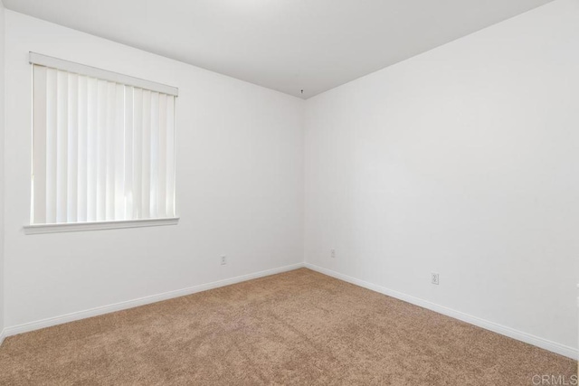 carpeted spare room featuring baseboards