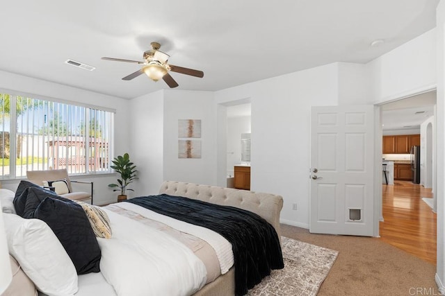 bedroom with light carpet, ceiling fan, visible vents, and freestanding refrigerator