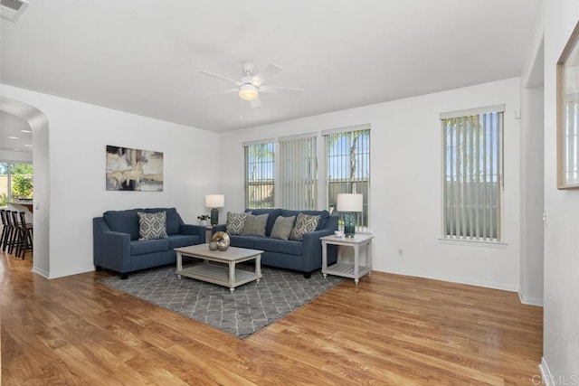 living area with visible vents, arched walkways, a ceiling fan, baseboards, and wood finished floors