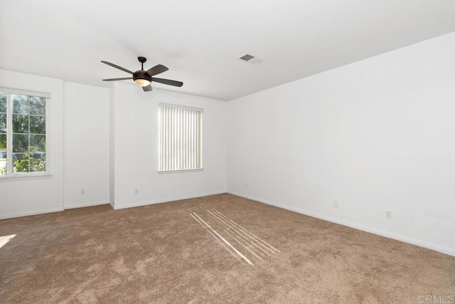 unfurnished room featuring baseboards, visible vents, ceiling fan, and light colored carpet