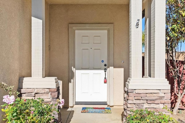 view of exterior entry featuring stone siding and stucco siding