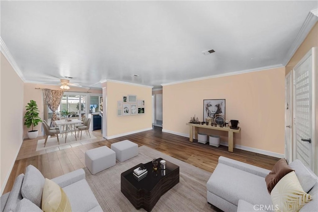 living room with light wood-style floors, a ceiling fan, baseboards, and crown molding