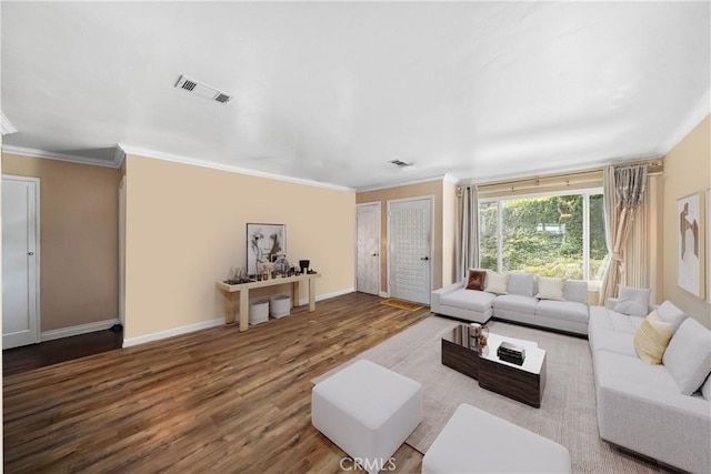 living area featuring baseboards, wood finished floors, visible vents, and crown molding