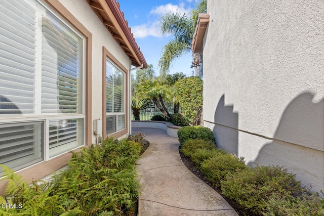 view of side of home featuring a patio area, fence, and stucco siding