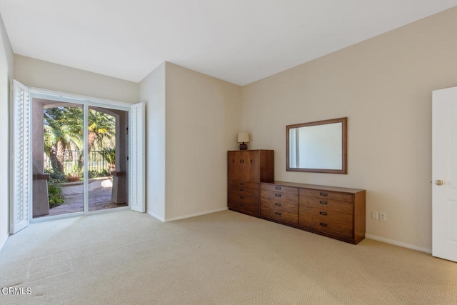 unfurnished bedroom with baseboards, light colored carpet, and access to exterior