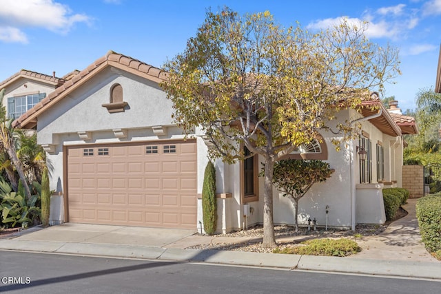 view of front of home featuring driveway, a tiled roof, an attached garage, and stucco siding