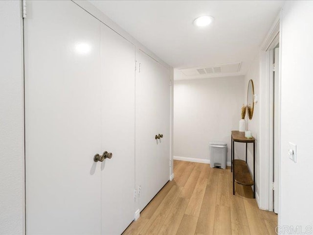 corridor with light wood finished floors, baseboards, and visible vents