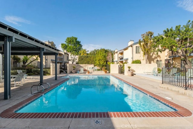 pool with a patio area, fence, and a residential view