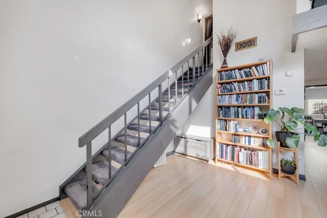 staircase featuring wood finished floors and a towering ceiling