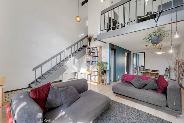 living room featuring wood finished floors, a high ceiling, and stairs