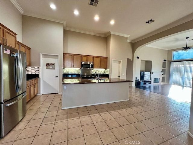 30659 Lajoe St, Menifee, CA 92584 - kitchen featuring appliances with stainless steel finishes, open floor plan, dark countertops, brown cabinets, and arched walkways