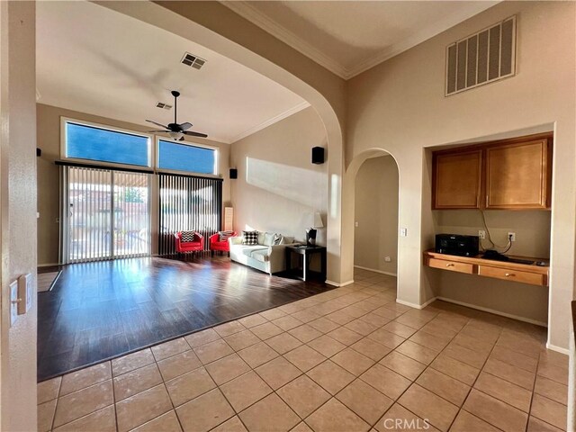 30659 Lajoe St, Menifee, CA 92584 - living area featuring arched walkways, light tile patterned floors, a ceiling fan, high vaulted ceiling, and crown molding