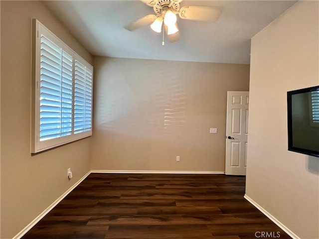 spare room featuring dark wood-style floors, baseboards, and a ceiling fan