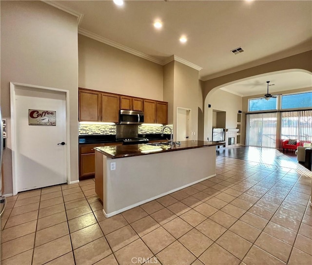 30659 Lajoe St, Menifee, CA 92584 - kitchen with stainless steel microwave, arched walkways, light tile patterned flooring, crown molding, and a high ceiling