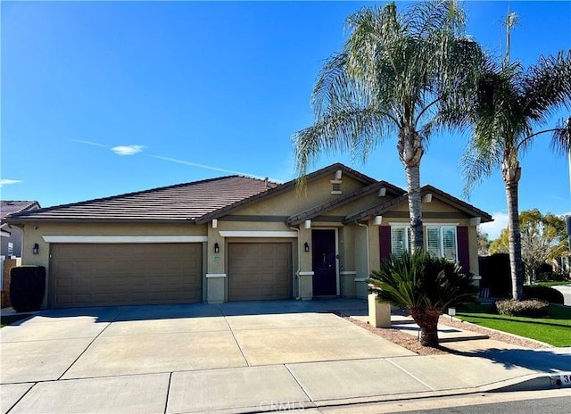 ranch-style house featuring a garage, a tile roof, concrete driveway, and stucco siding