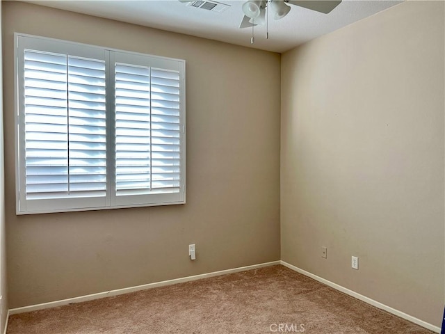 empty room featuring light carpet, visible vents, baseboards, and a ceiling fan