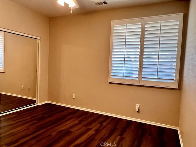 spare room with baseboards, visible vents, and wood finished floors