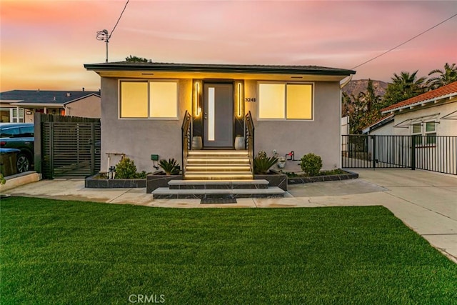 exterior space featuring a lawn, fence, and stucco siding