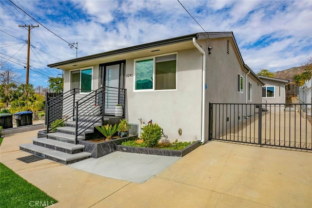 view of front of house featuring a patio area, fence, and stucco siding