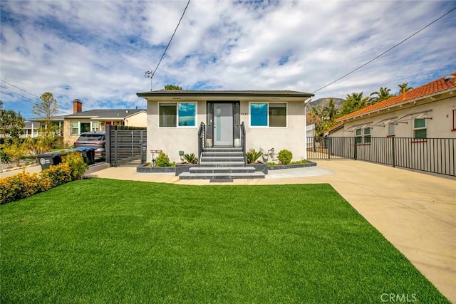 back of property featuring a gate, a lawn, fence, and stucco siding