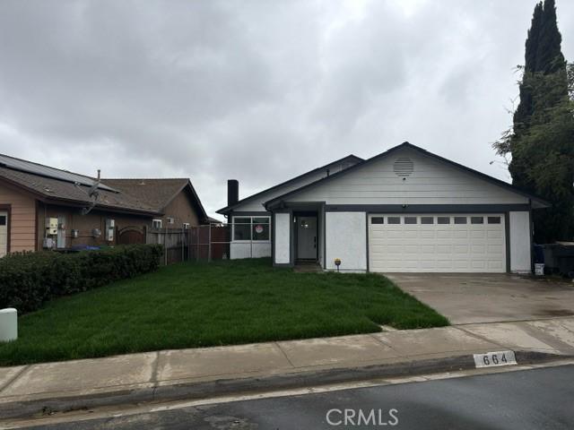 single story home featuring a garage, concrete driveway, fence, and a front lawn