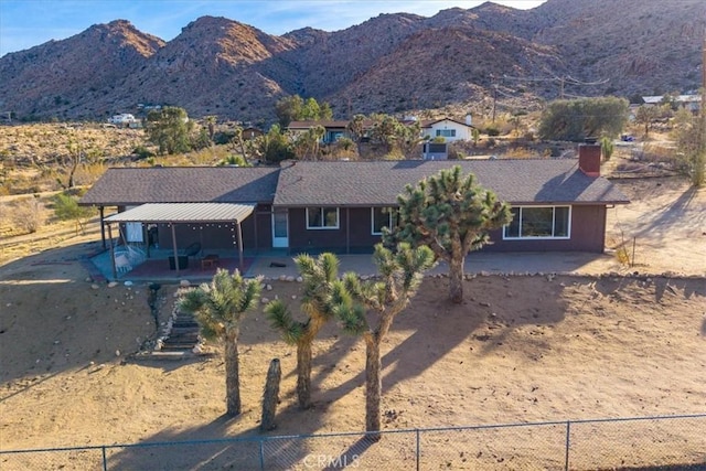 view of front of house with fence private yard, a mountain view, dirt driveway, and a patio