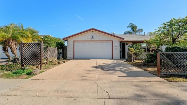 ranch-style house featuring a garage, driveway, and fence