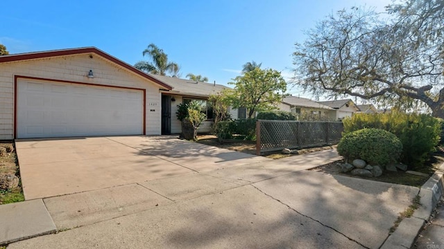 ranch-style home featuring concrete driveway, fence, and an attached garage