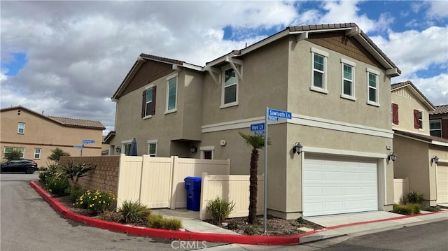 view of side of property featuring an attached garage, fence, and stucco siding