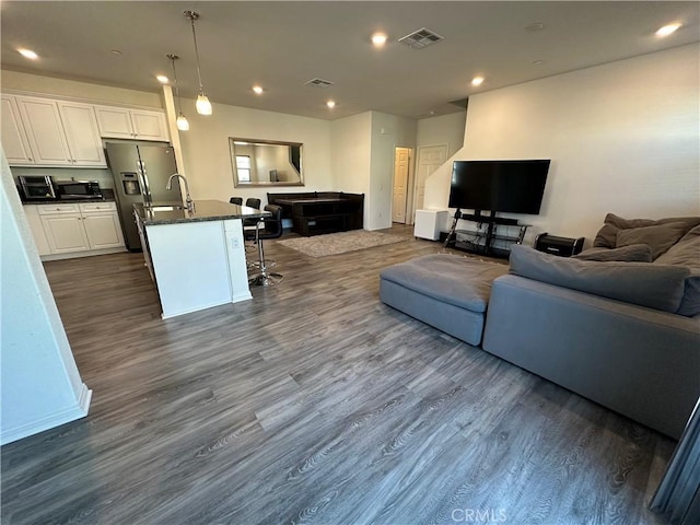 living room with dark wood-type flooring, visible vents, and recessed lighting