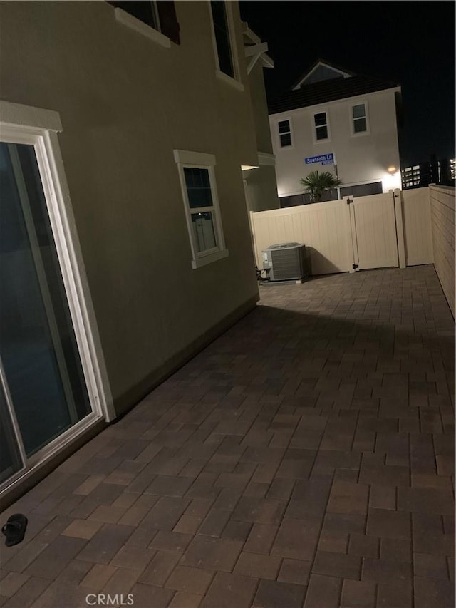 patio at night featuring central AC and fence