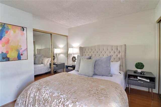 bedroom with a closet, a textured ceiling, and wood finished floors