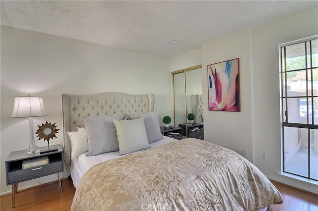 bedroom with a closet, a textured ceiling, and wood finished floors