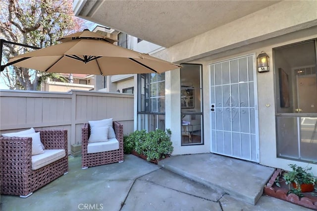 view of exterior entry featuring fence and a patio