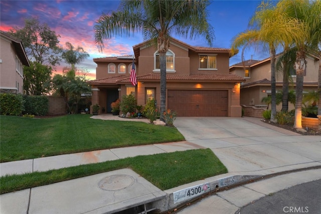 mediterranean / spanish-style home with an attached garage, concrete driveway, a tiled roof, stucco siding, and a front lawn