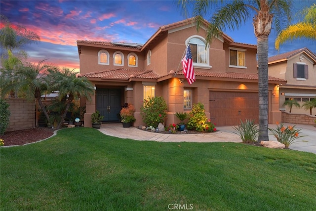 mediterranean / spanish-style house with an attached garage, a lawn, solar panels, and concrete driveway