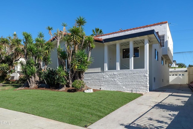 view of home's exterior with stone siding, a lawn, and stucco siding